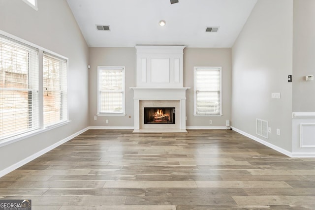 unfurnished living room with lofted ceiling, a large fireplace, and light wood-type flooring