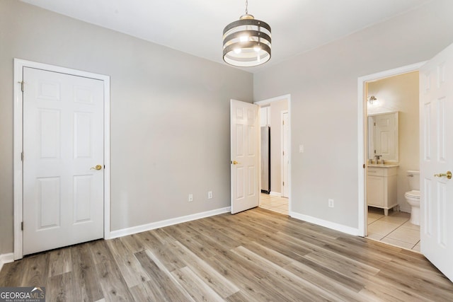 unfurnished bedroom with ensuite bath and light hardwood / wood-style flooring