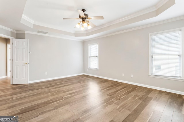 unfurnished room with a raised ceiling, wood-type flooring, ceiling fan, and crown molding