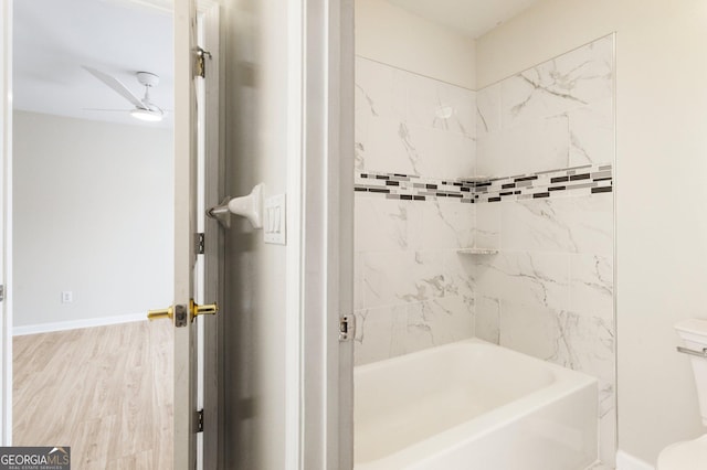 bathroom with tiled shower / bath, wood-type flooring, ceiling fan, and toilet