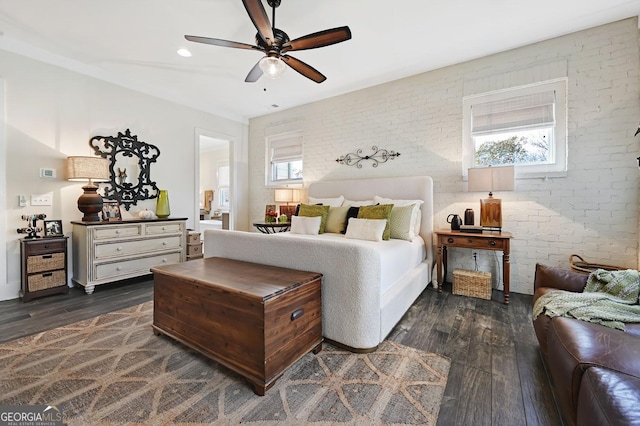 bedroom with dark wood-type flooring, ceiling fan, and brick wall