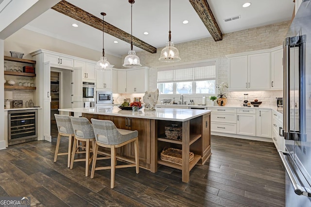 kitchen featuring decorative light fixtures, white cabinets, beverage cooler, a center island, and stainless steel appliances