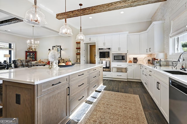 kitchen featuring pendant lighting, sink, appliances with stainless steel finishes, white cabinetry, and a spacious island