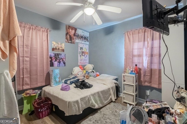 bedroom featuring hardwood / wood-style floors, crown molding, and ceiling fan