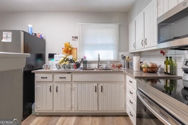 kitchen featuring sink, light hardwood / wood-style flooring, stainless steel appliances, and white cabinets