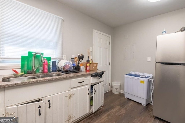 kitchen featuring washer / clothes dryer, sink, white cabinets, stainless steel fridge, and dark wood-type flooring