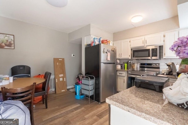 kitchen featuring stainless steel appliances, tasteful backsplash, white cabinets, and light wood-type flooring