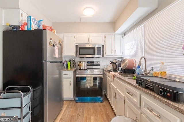 kitchen featuring sink, white cabinetry, tasteful backsplash, light wood-type flooring, and stainless steel appliances