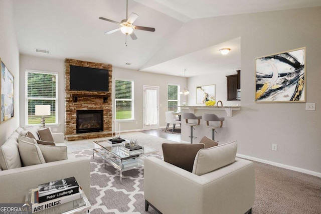 living room with ceiling fan, light colored carpet, a fireplace, and vaulted ceiling