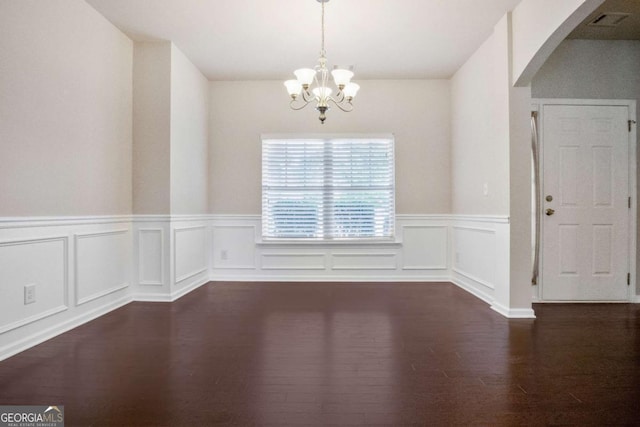 unfurnished dining area featuring an inviting chandelier and dark hardwood / wood-style flooring