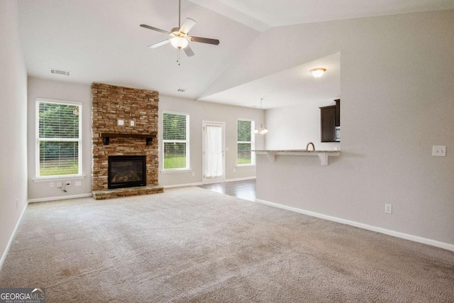 unfurnished living room featuring ceiling fan, a healthy amount of sunlight, vaulted ceiling, and carpet