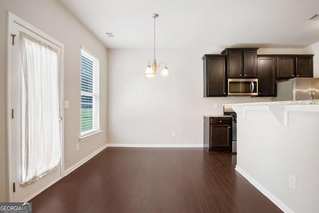 kitchen with stainless steel appliances, dark brown cabinets, a breakfast bar area, and pendant lighting