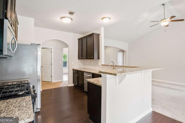 kitchen with a breakfast bar area, ceiling fan, stainless steel appliances, light stone counters, and kitchen peninsula