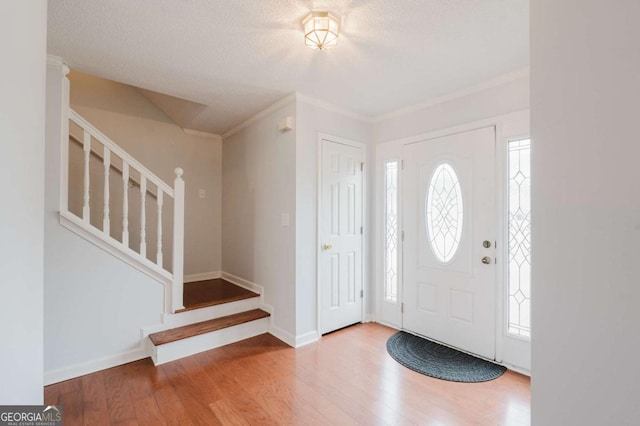 foyer featuring hardwood / wood-style flooring, crown molding, and a textured ceiling