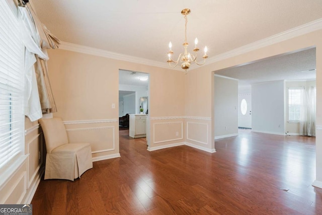 spare room featuring ornamental molding, wood-type flooring, and a notable chandelier