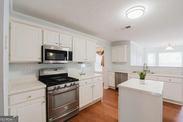 kitchen with white cabinetry, stainless steel appliances, sink, and a kitchen island