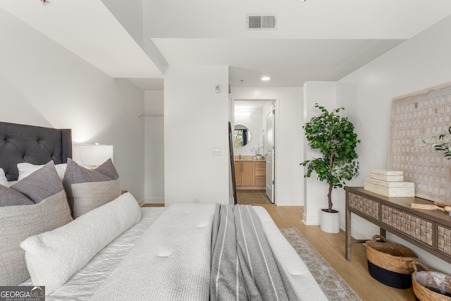 bedroom featuring ensuite bathroom and light hardwood / wood-style flooring