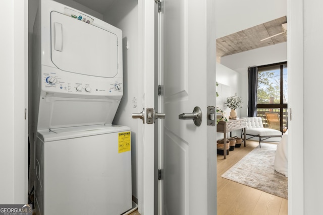 clothes washing area with stacked washer and clothes dryer and light hardwood / wood-style floors