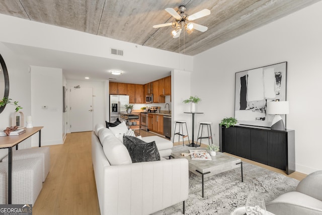 living room featuring ceiling fan, sink, and light hardwood / wood-style floors