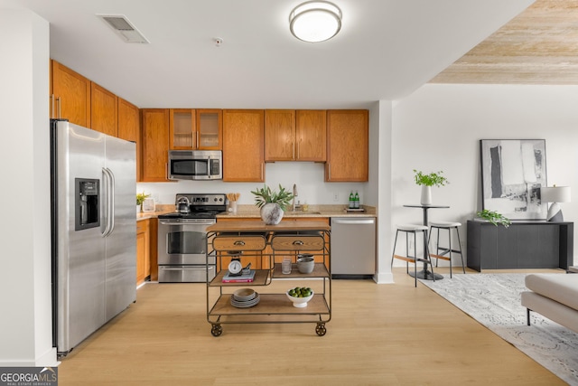 kitchen featuring appliances with stainless steel finishes, light hardwood / wood-style floors, and sink