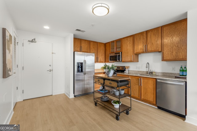 kitchen featuring stainless steel appliances, sink, and light hardwood / wood-style flooring