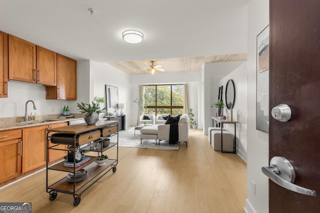 kitchen with sink, ceiling fan, and light wood-type flooring