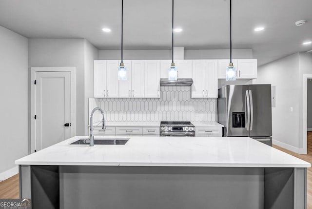 kitchen featuring white cabinetry, hanging light fixtures, stainless steel appliances, and an island with sink