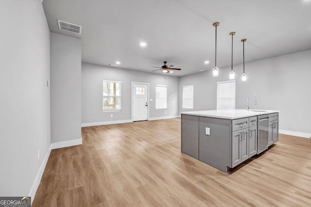 kitchen with sink, a center island with sink, stainless steel dishwasher, gray cabinets, and pendant lighting