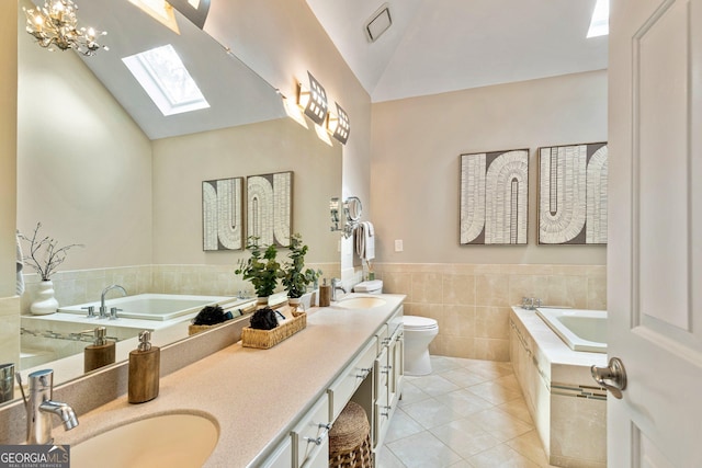 bathroom featuring vanity, a relaxing tiled tub, vaulted ceiling, tile patterned floors, and toilet