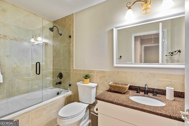 full bathroom featuring tile walls, vanity, shower / bath combination with glass door, and toilet