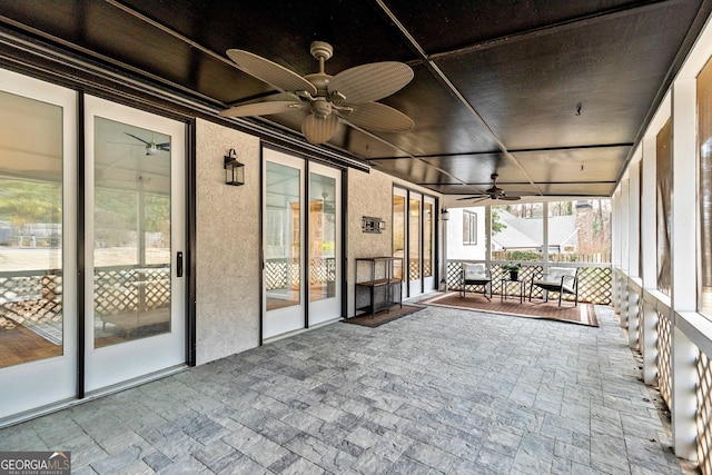 unfurnished sunroom with ceiling fan