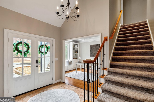 tiled entrance foyer featuring an inviting chandelier, lofted ceiling, and french doors