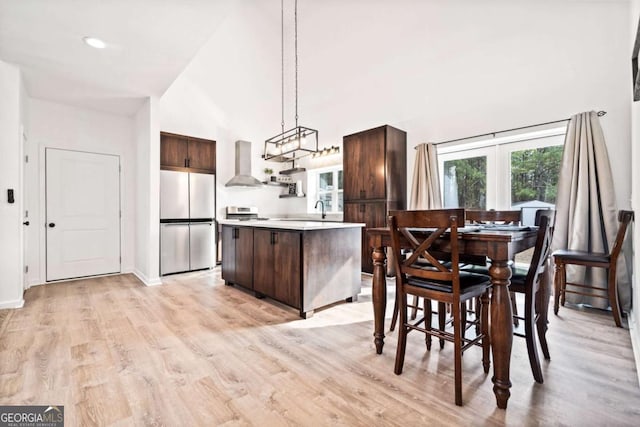 dining space with sink, a towering ceiling, and light hardwood / wood-style floors