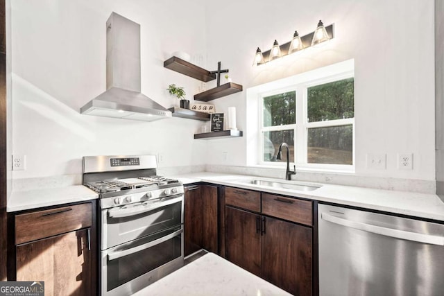 kitchen with wall chimney exhaust hood, dark brown cabinetry, stainless steel appliances, and sink