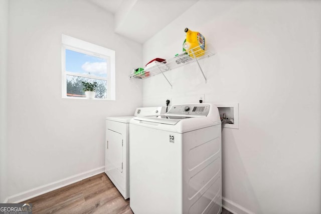 clothes washing area featuring washer and clothes dryer and light wood-type flooring