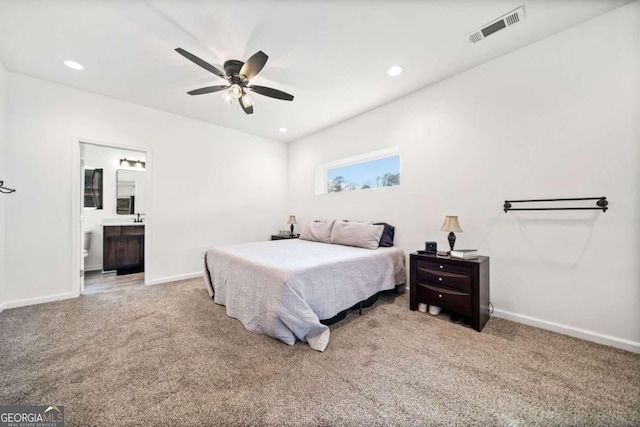 bedroom with ceiling fan, connected bathroom, and light carpet