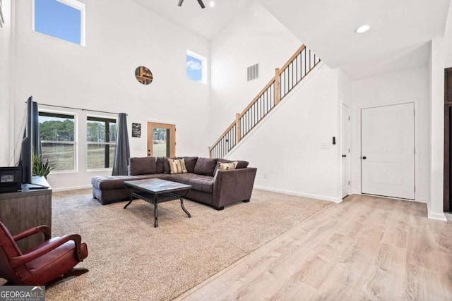 living room featuring a towering ceiling and light hardwood / wood-style flooring