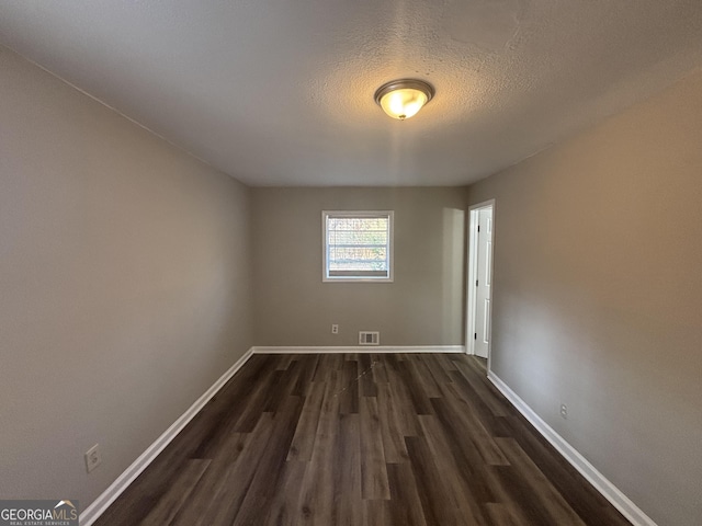 unfurnished room with dark hardwood / wood-style flooring, built in features, and a textured ceiling