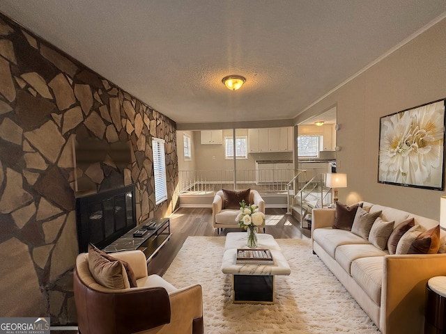 living room featuring ornamental molding, a fireplace, hardwood / wood-style floors, and a textured ceiling