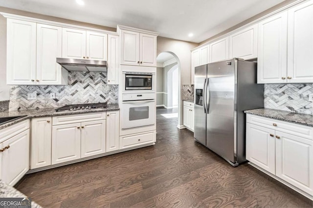 kitchen with dark stone countertops, stainless steel appliances, dark hardwood / wood-style flooring, and white cabinets