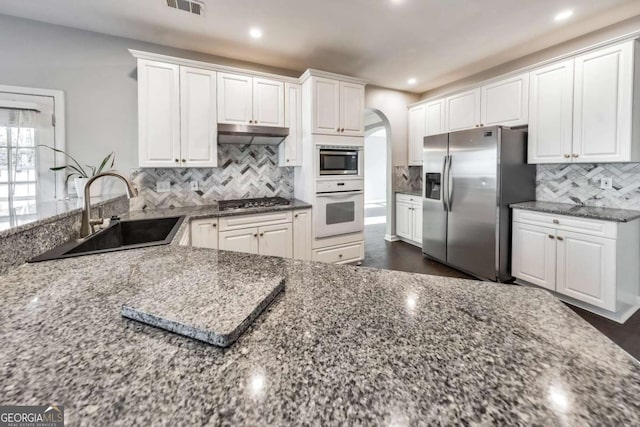 kitchen with dark stone countertops, sink, stainless steel appliances, and white cabinets