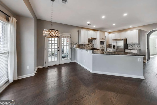 kitchen with hanging light fixtures, kitchen peninsula, white cabinets, and appliances with stainless steel finishes