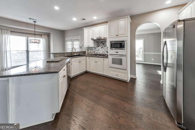 kitchen with sink, white cabinets, hanging light fixtures, kitchen peninsula, and stainless steel appliances