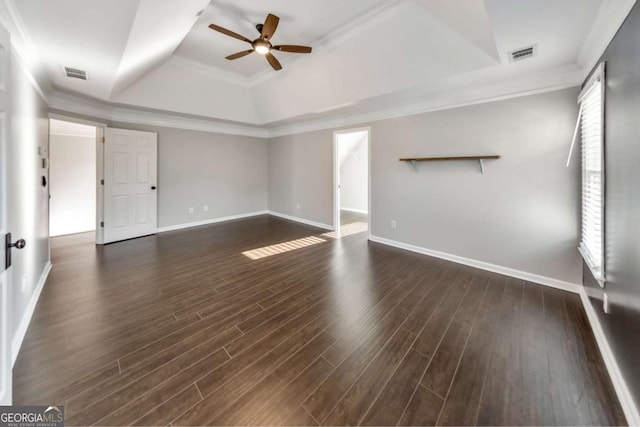 spare room featuring dark hardwood / wood-style floors, ornamental molding, and a raised ceiling