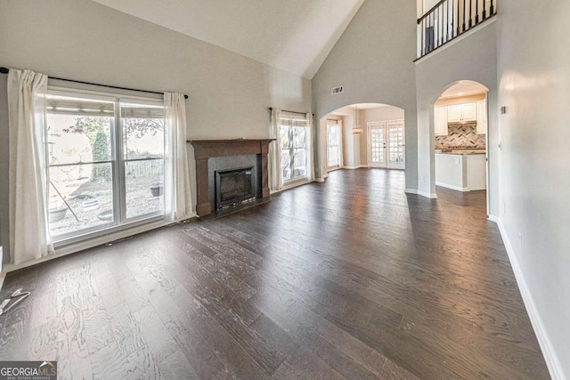 unfurnished living room featuring dark wood-type flooring and high vaulted ceiling