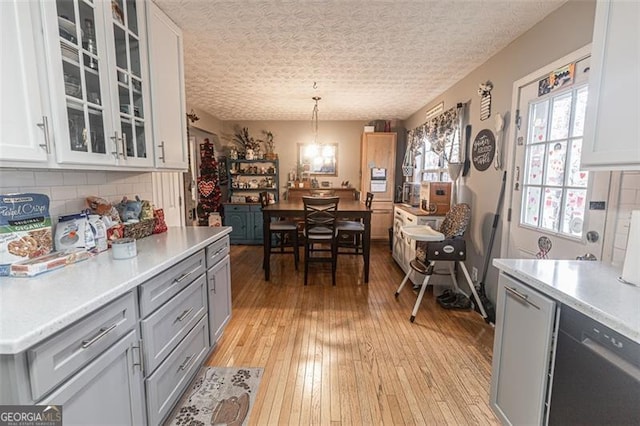 kitchen featuring decorative light fixtures, light hardwood / wood-style floors, decorative backsplash, and white cabinets