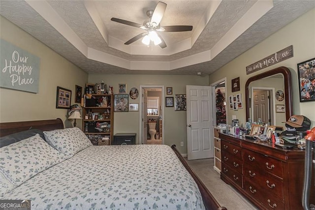 carpeted bedroom featuring ceiling fan, a tray ceiling, and a textured ceiling