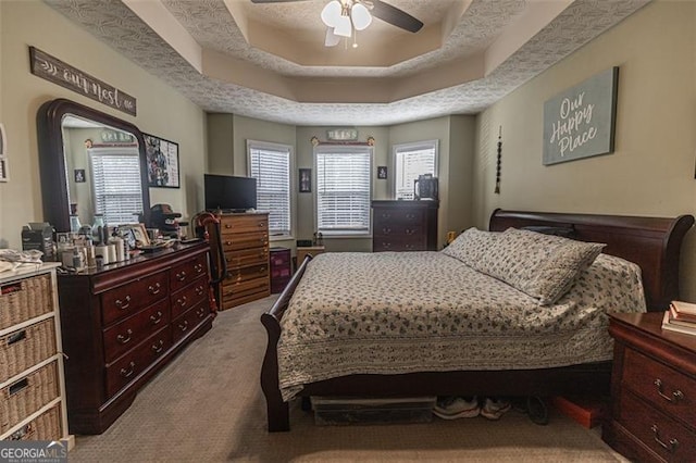 bedroom featuring ceiling fan, light colored carpet, a raised ceiling, and a textured ceiling