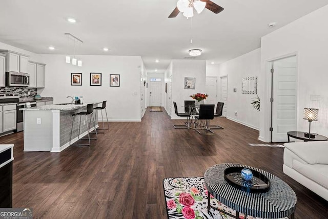 living room with ceiling fan, sink, and dark hardwood / wood-style flooring