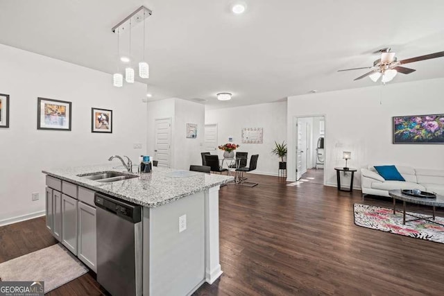 kitchen with sink, light stone counters, decorative light fixtures, a center island with sink, and stainless steel dishwasher